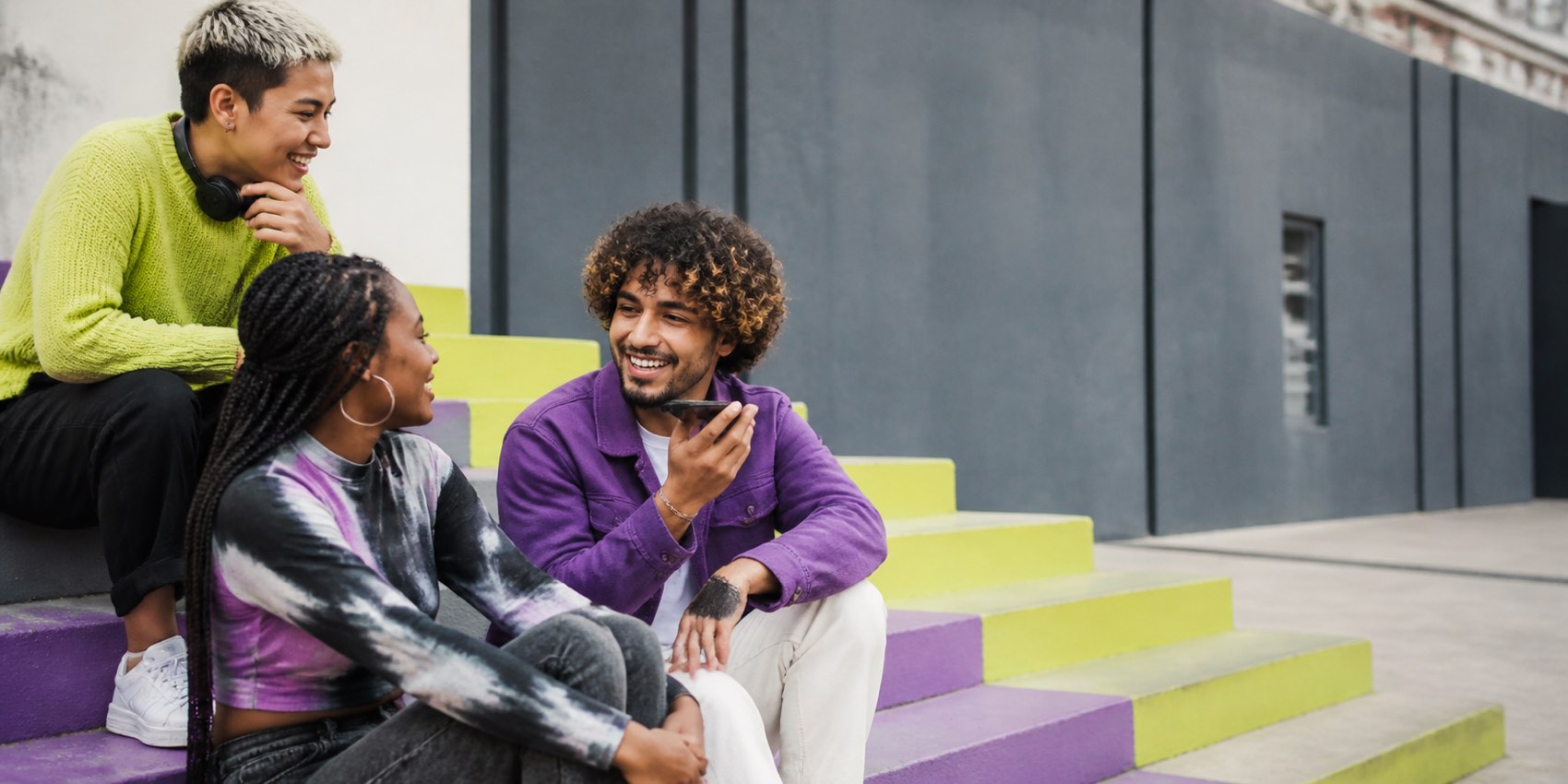 Friends sharing a voice message on colorful city steps